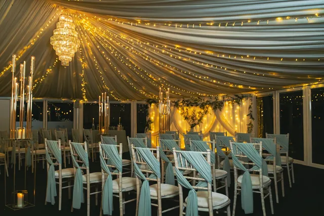 The Arboretum lit gold for an evening ceremony, chairs dressed in sage