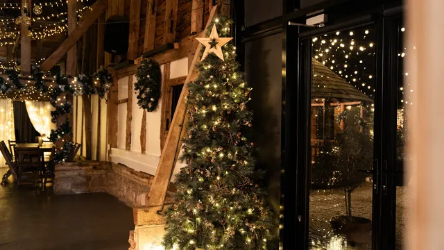A lit Christmas tree beside the barn's timber frame
