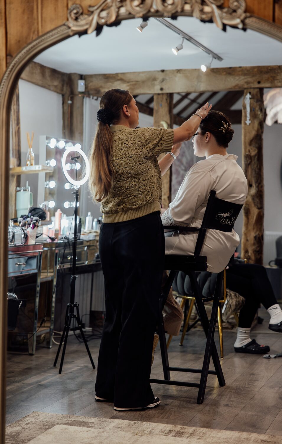 A hair stylist at work at the lit vanity mirrors