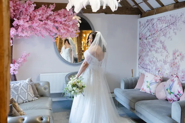 A bride from behind beneath the feather chandelier in the Blossom suite, her train spread across the floor