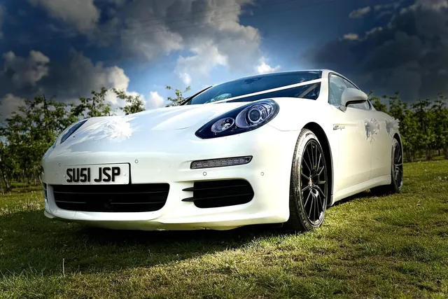 A white Porsche Panamera wedding car under a dramatic sky