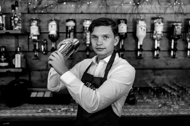 A bartender at work behind the bar in black and white