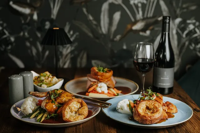 A table of plated dishes with red wine