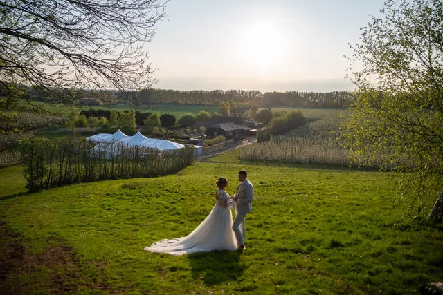 A couple in the field with the Arboretum behind