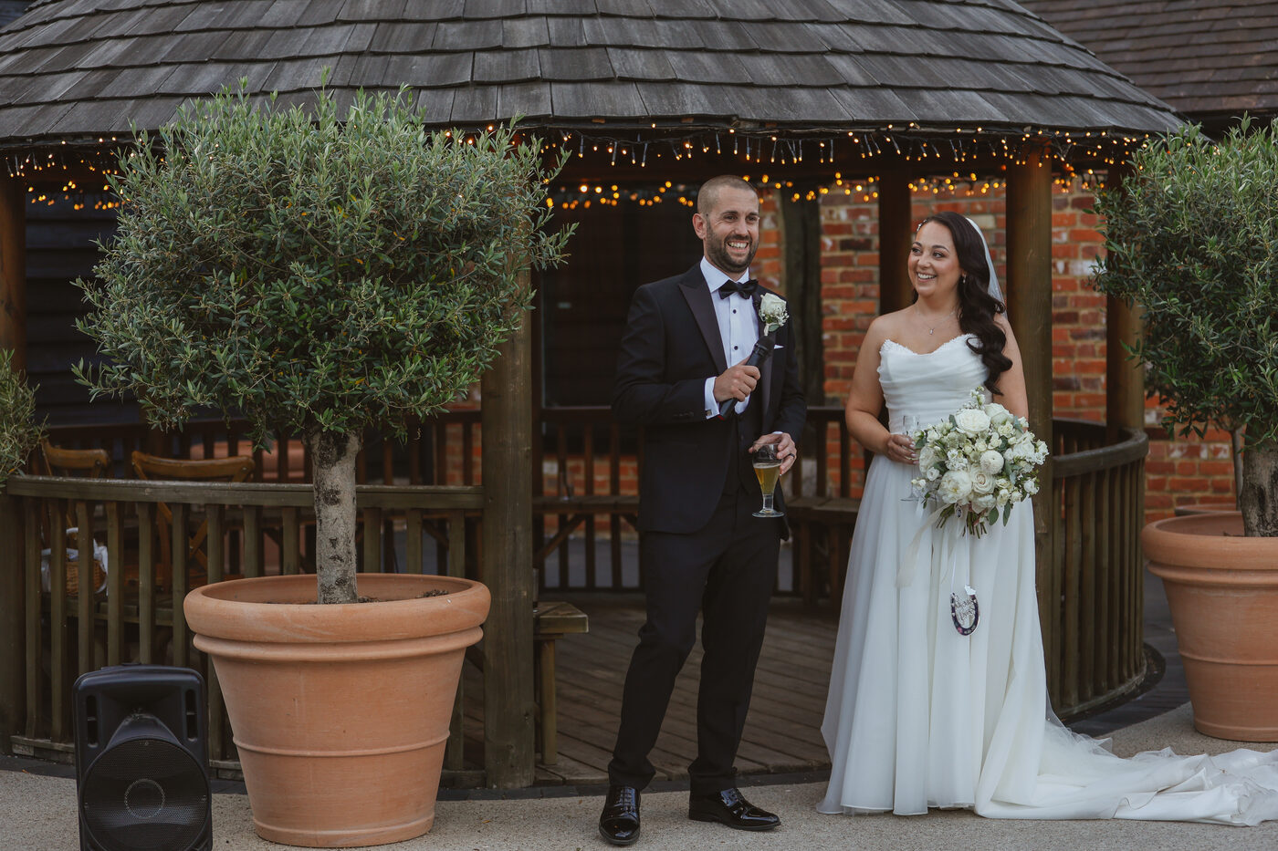 A newly married couple beside the Courtyard gazebo at The BarnYard, olive trees in terracotta pots either side
