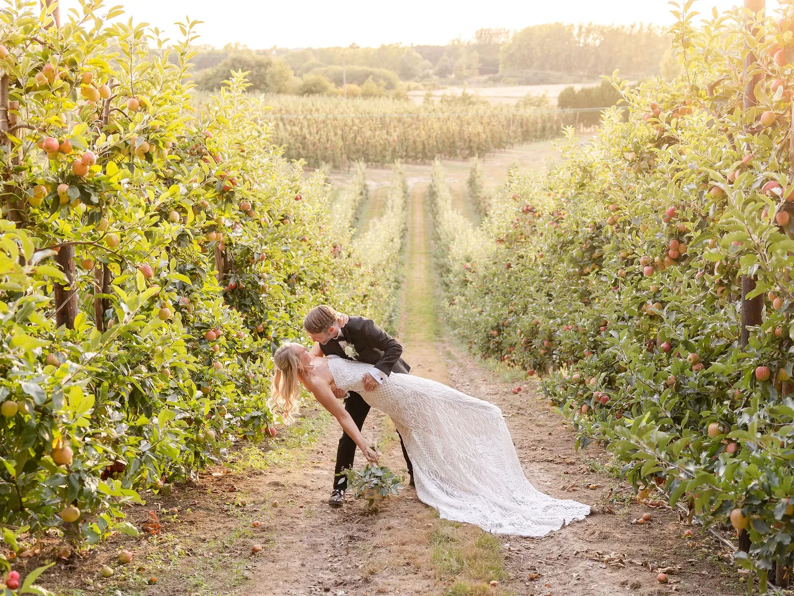 A wedding couple walking through the orchards at The BarnYard at golden hour